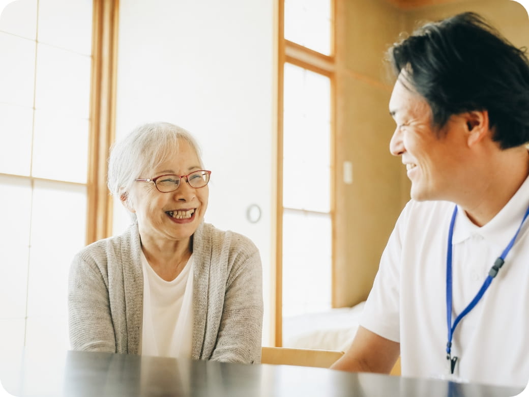 笑顔で会話をする高齢女性と介護士の男性