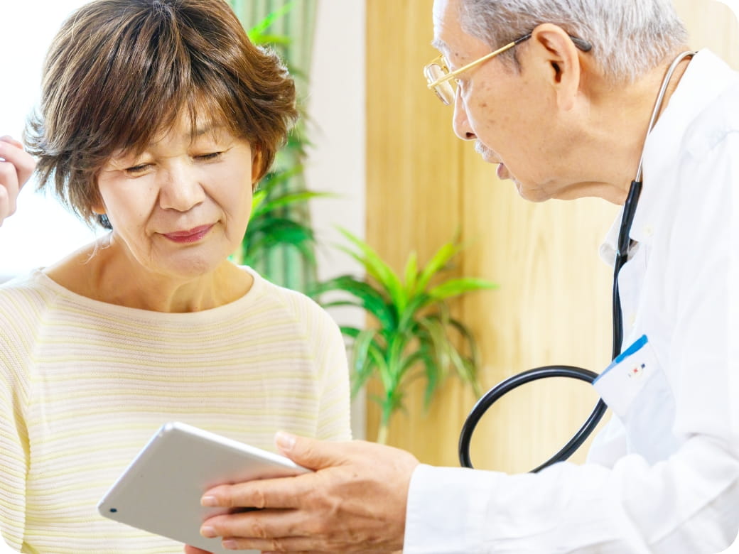 医師がタブレットを使って説明し、高齢女性が内容を真剣に確認している様子