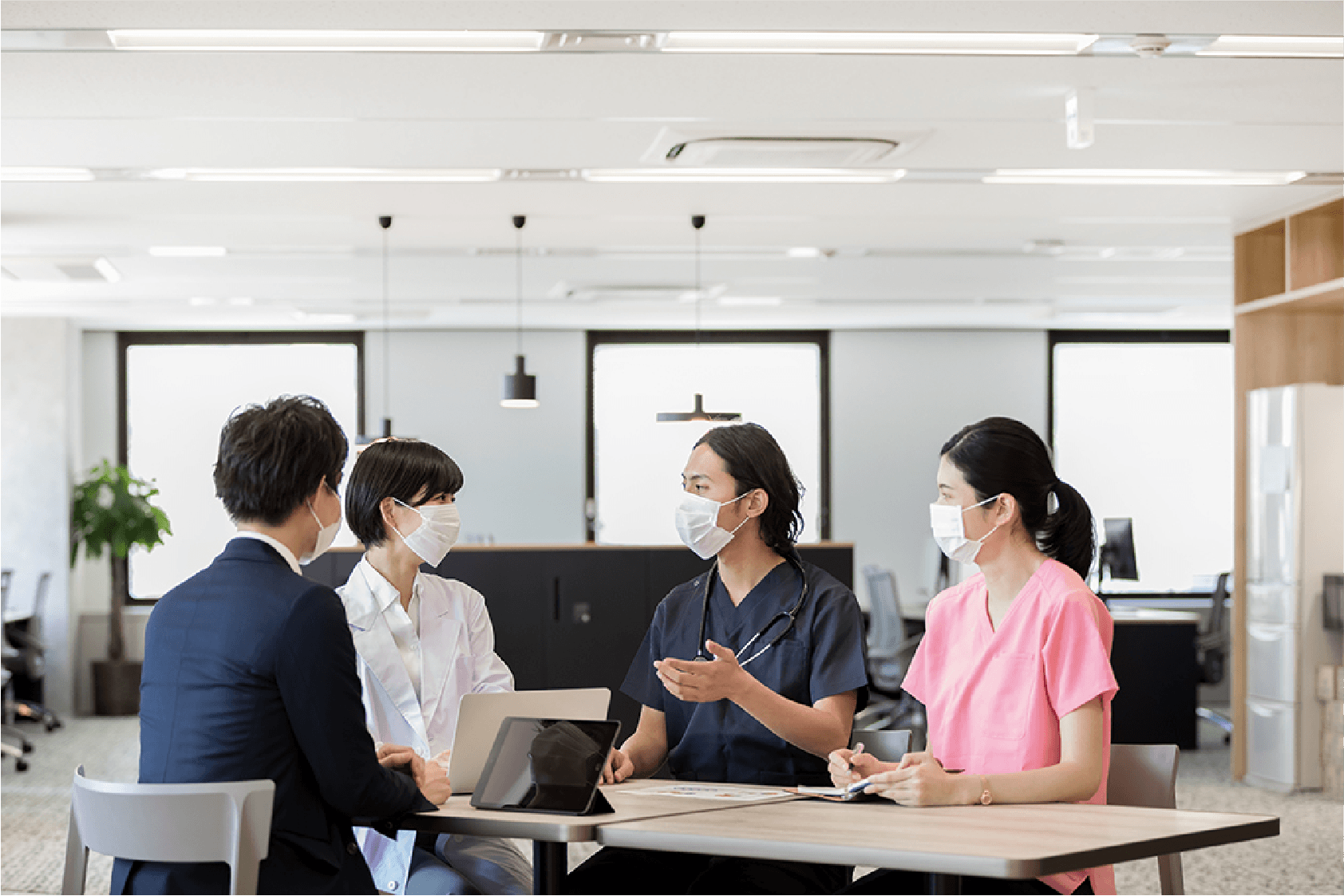 病院内の会議室で医師や看護師、管理者がミーティングをしている様子